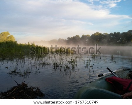 Morning fishing in Belarus on the Pripyat River. The first rays of the summer sun, dawn, fog to fall into the water. Fishing on an inflatable boat with a motor. Wild Belarusian nature. Before sailing.