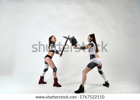 beautiful girls in costumes of robots fight a battle ax and a war hammer