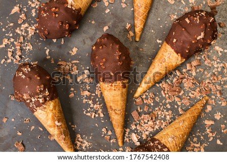 Chocolate ice cream cones with peanuts chips on a metal table in a close up view