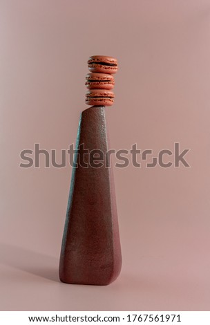 Minimalistic food art concept, textured austere vase with stack of macarons on top.