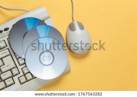 Old-fashioned retro keyboardб CD's and pc mouse on yellow background. Top view