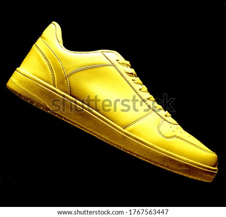 One golden sneaker isolated on black background 