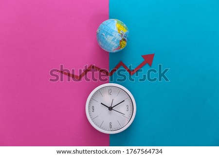 White clock and globe, red growth arrow on pink blue background. Top view