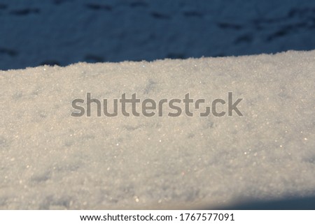 Close up picture of a window seal covered with snow with footprints in the snow on the street down in soft focus in the background