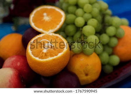plate with a variety of fruits and wedding rings in orange