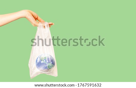 Hand holding the planet earth in a plastic bag on light green background, Pollution from plastic and green day concept,  Elements of this image furnished by NASA, Time is running for earth concept