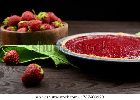 Strawberry pie closeup in baking dish with fresh berries on wooden table background, selective focus, side view