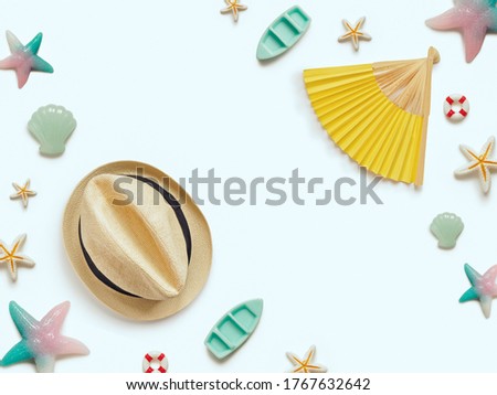 Creative travel background. Layout of various sea figures (starfish, boats, anchor, lifebuoy, shells), a straw hat and a paper fan. Preparing for vacation and travel. Flat lay. Copy space.