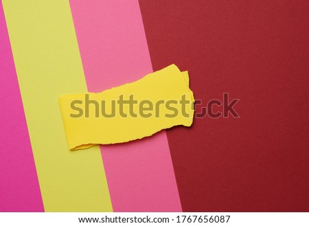 torn piece of yellow paper on a colored background, abstract backdrop, close up
