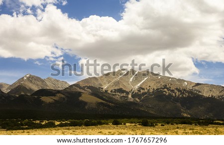 mountain with little snow on the top and beautiful white clouds