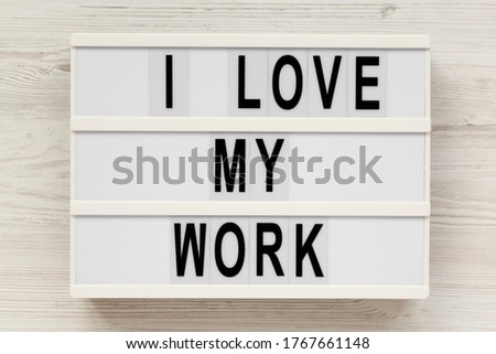 'I love my work' on a lightbox on a white wooden background, top view. Flat lay, from above, overhead. 