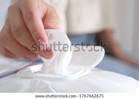 Woman taking wet wipe out of pack against blurred background, closeup Royalty-Free Stock Photo #1767662675