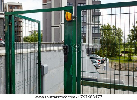 Front door of the courtyard. Metal Wire Fence.Green metal driveway entrance gates. Remote control to open swing gate door by motor automation is home security system