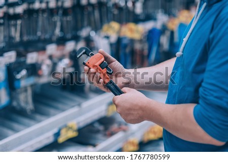 The buyer in the hardware store selects the goods. A man holds a wrench in his hand Royalty-Free Stock Photo #1767780599