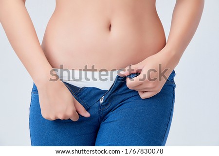 Image of belly and waist of slim woman taking off her jeans Isolated on white background