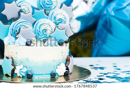 Beautiful birthday cake. The top of the cake is made of gingerbread in the shape of stars and delicate meringues. Balloons are in the background. Copy space for text. The concept of the celebration.