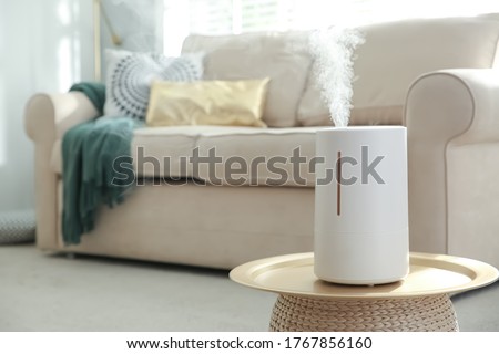 Modern air humidifier on table in living room. Space for text Royalty-Free Stock Photo #1767856160