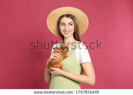 Young woman with adorable rabbit on pink background. Lovely pet