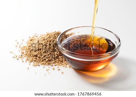 Pour the oil into the sesame oil placed on a white background. Royalty-Free Stock Photo #1767869456
