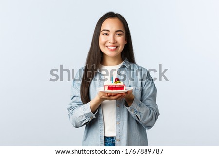 Social distancing lifestyle, covid-19 pandemic, celebrating holidays during coronavirus concept. Cheerful pretty asian girl celebrate birthday, smiling holding bday cake with candle