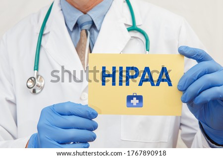Close-up of a male doctor in gloves holding a sign with the text HIPAA The Health Insurance Portability and Accountability Act of 1996