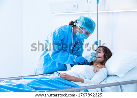 Doctor examining female patient in critical health conditions using a stethoscope in the intensive care unit of a modern hospital during covid-19 pandemic Royalty-Free Stock Photo #1767892325