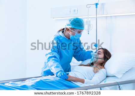 Nurse comforting a sick patient wearing a mask for positive pressure oxygen for respiratory diseases during the Covid-19 pandemic in the ward as she lies in bed