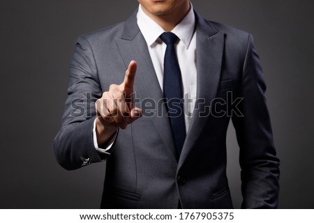 Portrait Half Body 40s Asian Business Man gray formal Suit necktie, no face, studio lighting dark background, Tanned skin Male Model touch digital screen, point to camera, copy space