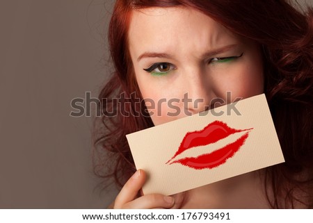 Happy pretty woman holding card with kiss lipstick mark on gradient background