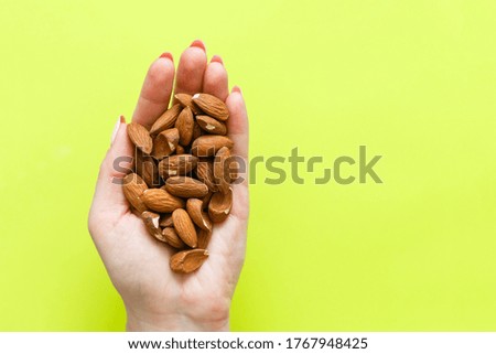 image of hands holding hazelnuts over light green background