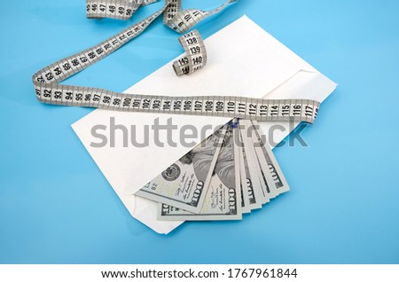 Money in an envelope with a tape measure. Photo of dollars in an envelope. Inflation. Price increase. The greedy concept of corruption. Bribe an idea. The economic crisis, unemployment. Blue backgroun