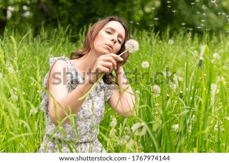A woman blows a dandelion in nature. Happy female walking in the Park.