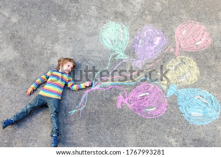 Kid boy having fun with colorful balloons drawing with chalks