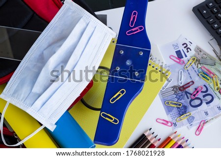 Colorful school supplies on the white surface with face mask.