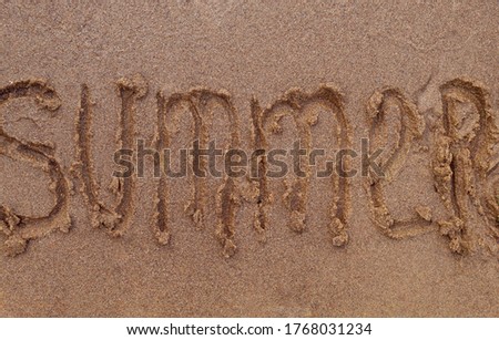 Inscription of the word summer on the sandy shore