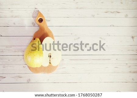Fresh pear cut in half on pear shaped wooden board on gray wooden background, top view, copy space