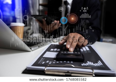Double exposure of businessman hands working on calculator with digital marketing virtual chart, Abstract icon, Business strategy concept, Background toned image blurred.