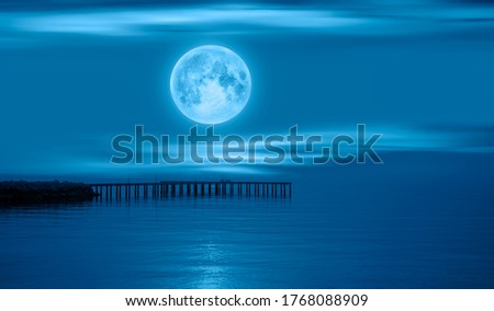Night sky with full moon in the clouds with pier "Elements of this image furnished by NASA