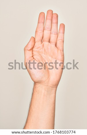 Hand of caucasian young man showing fingers over isolated white background stretching and reaching with open hand for handshake, showing palm