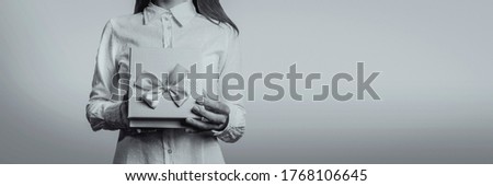 Young girl opens a gift box. The face of the girl is not visible. Black and white image