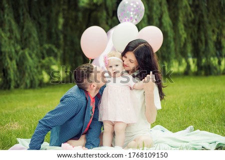 young happy family relaxing with little daughter girl on summer park grass 