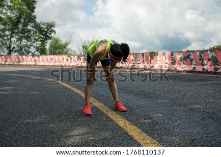 Tired woman ultra marathon runner have a rest on rainforest trail Royalty-Free Stock Photo #1768110137