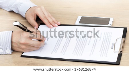 Girl sits at a table and signs a contract. Business