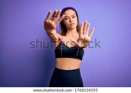 Young beautiful sporty girl doing sport wearing sportswear over isolated purple background doing frame using hands palms and fingers, camera perspective