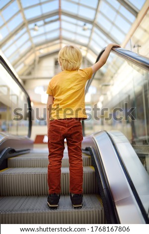 Behavior rules on escalator, in transport, on streets of city. Little child standing on moving staircase. Safety kids. Royalty-Free Stock Photo #1768167806
