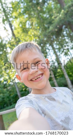 Authentic Funny small boy taking selfies and laughing. Smiling cute boy taking photos and facetime chatting with family. Vertical photo.