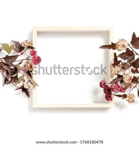 Flower composition. An empty wooden picture frame and blooming garden or field plants are on a white background. Summer or autumn concept. Flat lay. Copy space.