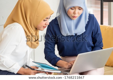 Two young muslim businesswomen discussing a work in the office.