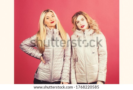 Two young beautiful blond smiling girls in trendy spring clothes. Positive models having fun.