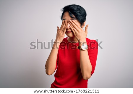 Young beautiful asian girl wearing casual red t-shirt standing over isolated white background rubbing eyes for fatigue and headache, sleepy and tired expression. Vision problem